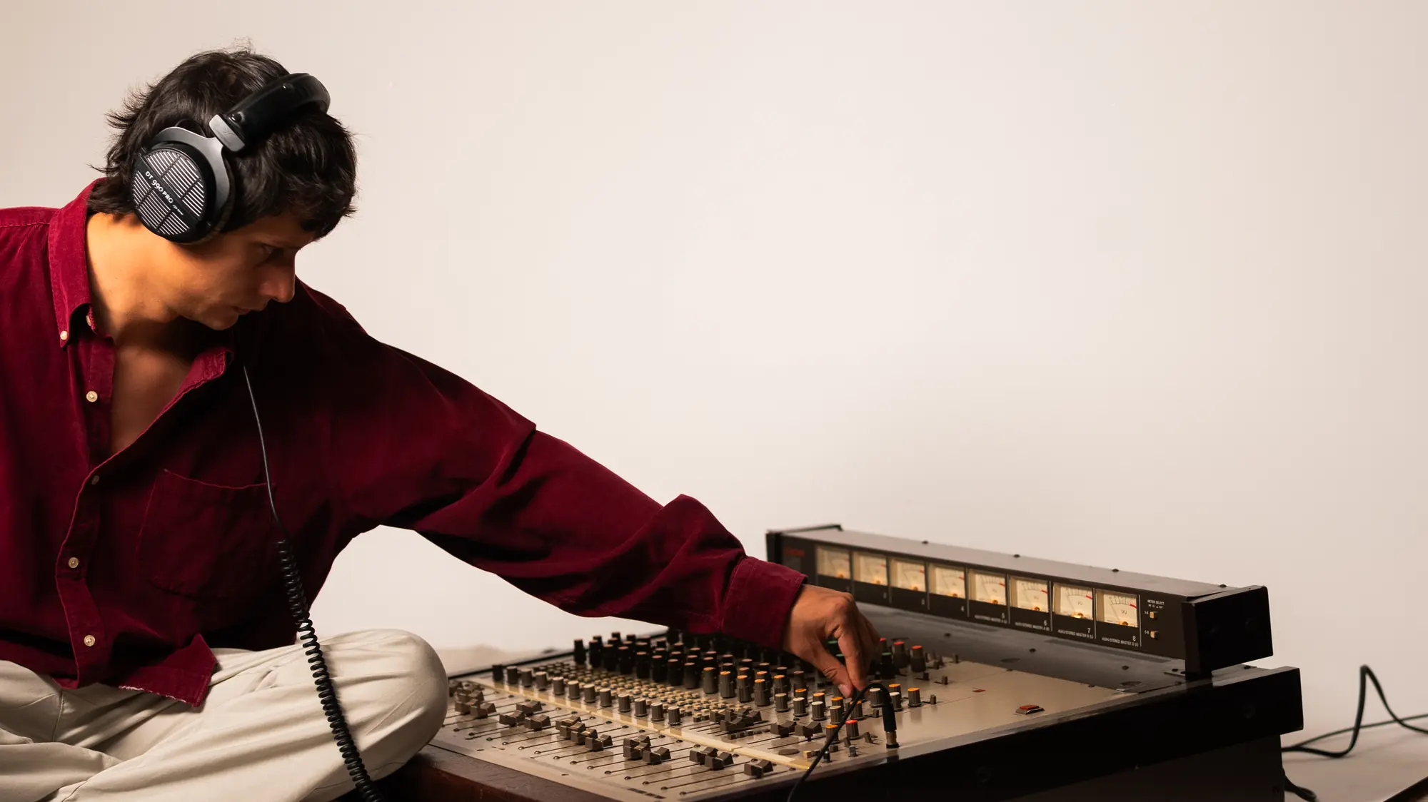 Engineer with headphones working at an analog console